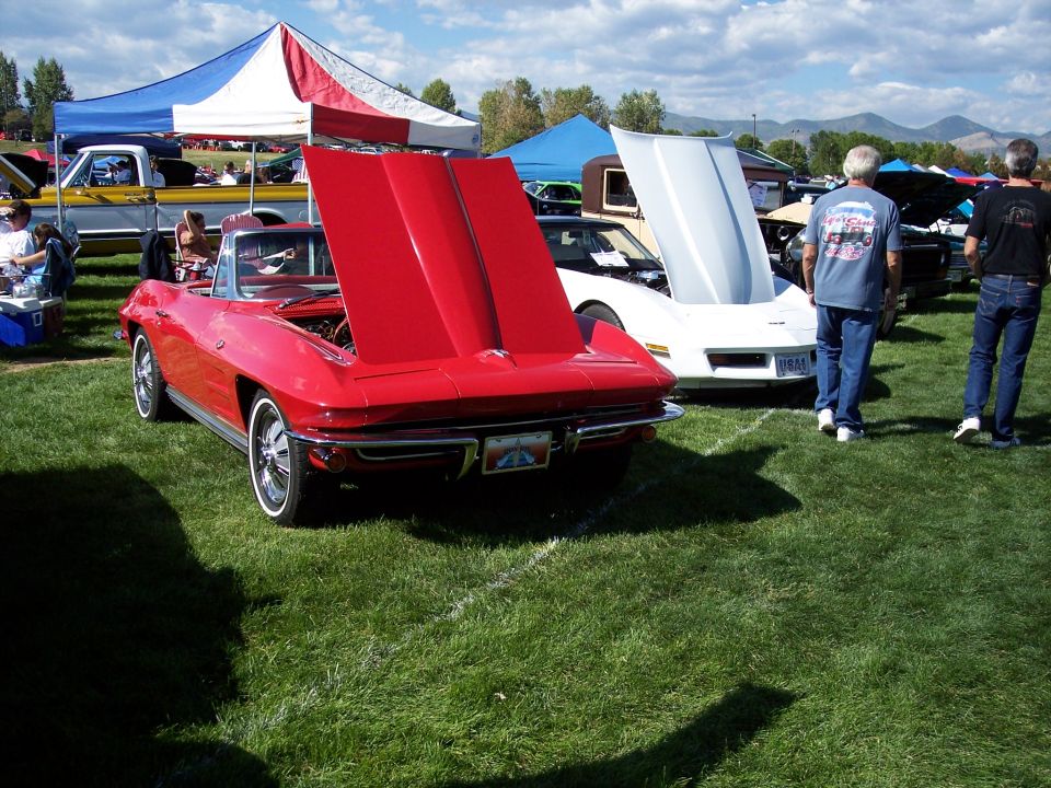 Red convertible sports car with hood open, rear view. Whitewall tires and chrome bumper visible