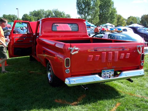 1972 Ford Ranchero - Rear view of a red pickup truck at an outdoor car show, with other vehicles visible.