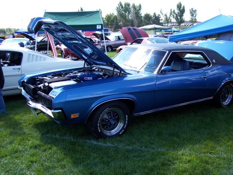 1972 Ford Ranchero - A blue 1970 Mercury Cougar XR7 is displayed with its hood open at an outdoor car show, alongside other vehicles.