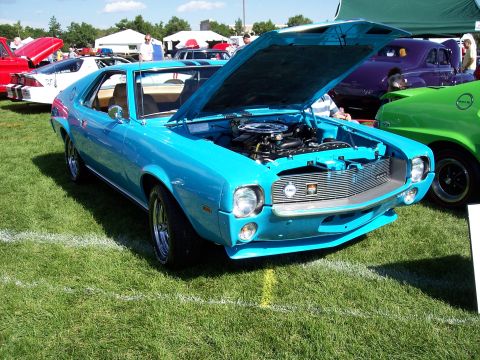 1972 Ford Ranchero - A blue 1968 AMC AMX is displayed with its hood open at an outdoor car show.