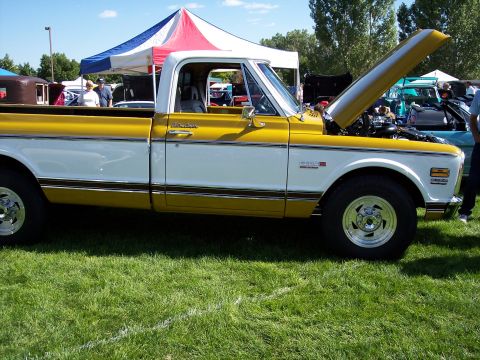 1972 Ford Ranchero - A classic pickup truck is displayed at an outdoor car show with tents and other vehicles in the background.