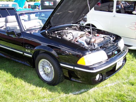 1972 Ford Ranchero - A black convertible with its hood open is parked on grass next to a white car.