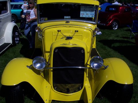 1972 Ford Ranchero - A bright yellow vintage truck with flame pinstriping on the hood is displayed at an outdoor car show.