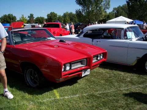 1972 Ford Ranchero - Two classic cars are parked on a grassy field at an outdoor event, with people and tents in the background.