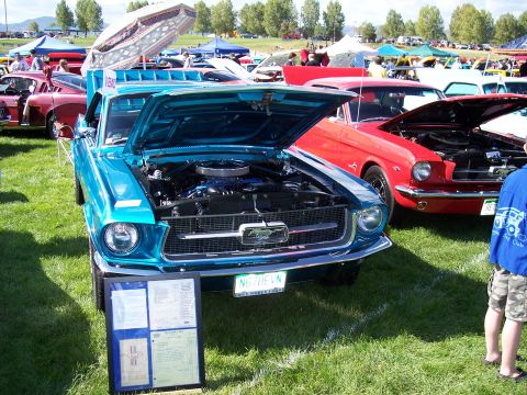 1972 Ford Ranchero - A blue classic car is displayed with its hood open at an outdoor car show, with other vehicles and tents in the background.