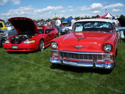 1972 Ford Ranchero - A bright red 1956 Chevrolet Bel Air is displayed at an outdoor car show, parked on a grassy field under a blue sky.