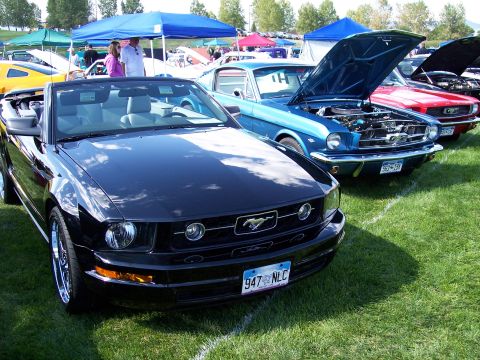 1972 Ford Ranchero - Several Ford Mustangs are displayed on a grassy field under tents at an outdoor car show.