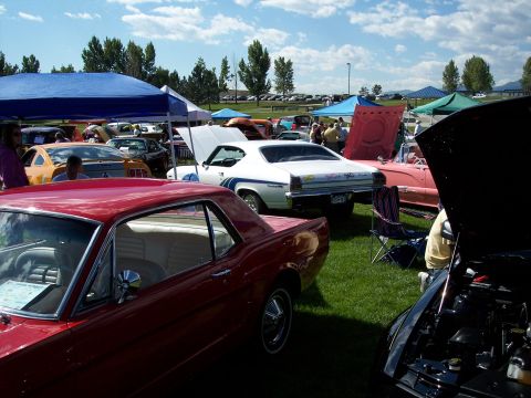 1972 Ford Ranchero - Multiple classic cars are displayed on a grassy field under a blue sky with scattered clouds.