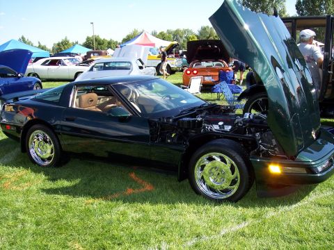 1972 Ford Ranchero - A dark green Chevrolet Corvette C4 is displayed with its hood open at an outdoor car show.