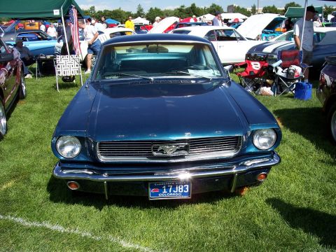 1972 Ford Ranchero - A blue 1965 Ford Mustang is displayed at an outdoor car show, its distinctive grille and emblem.