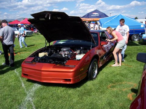 1972 Ford Ranchero - Car show scene with an orange Pontiac Firebird on display with its hood up.