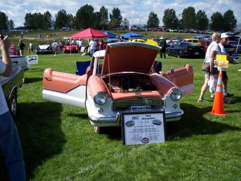 1972 Ford Ranchero - A 1957 Nash Metropolitan pickup truck is displayed with its hood and doors open at an outdoor car show.