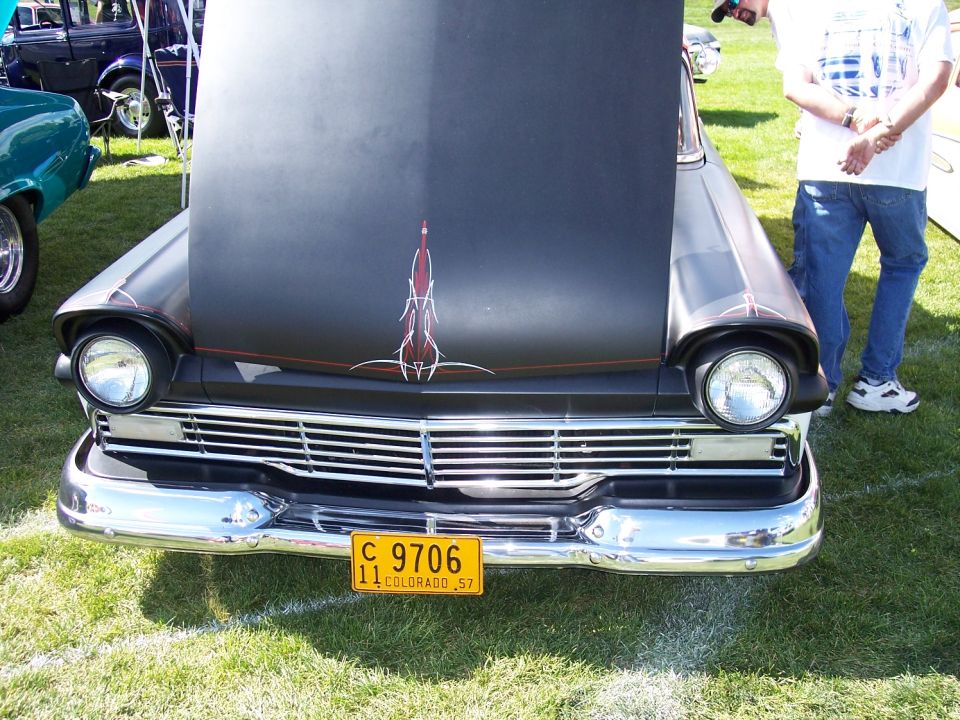 Front view of a black hot rod with hood open, pinstripe art on hood, and a yellow Colorado license plate reading 'C 9706 11 COLORADO 57'