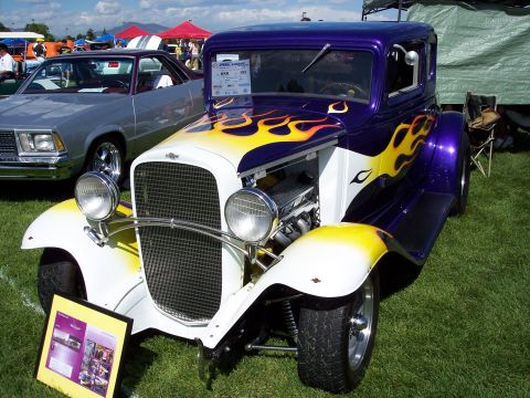 1972 Ford Ranchero - A custom hot rod with flame graphics is displayed at an outdoor car show, with another vehicle visible in the background.