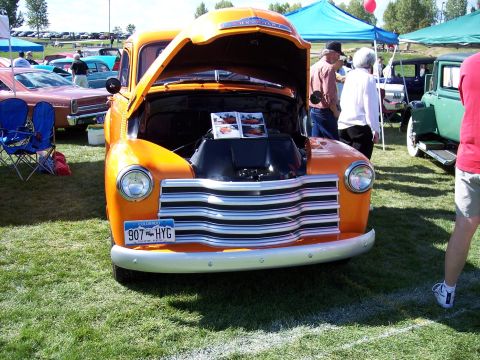 1972 Ford Ranchero - A classic orange Chevrolet truck is displayed with its hood up at an outdoor event.