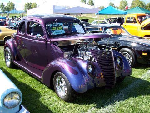 1972 Ford Ranchero - A custom purple hot rod coupe with an exposed engine sits on display at an outdoor car show.