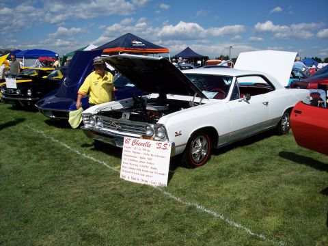 1972 Ford Ranchero - A white 1967 Chevelle SS is displayed at an outdoor car show with its hood open, next to other vehicles.