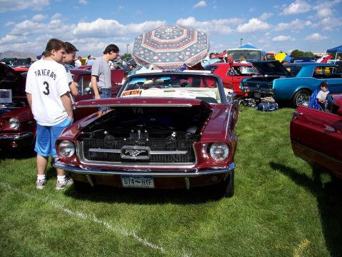 1972 Ford Ranchero - A classic Ford Mustang convertible is displayed at an outdoor car show with other vehicles and attendees.