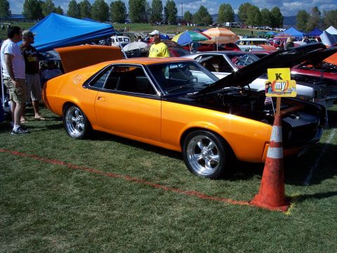 1972 Ford Ranchero - This orange muscle car, likely from the early 1970s, is displayed with its hood open at an outdoor event.