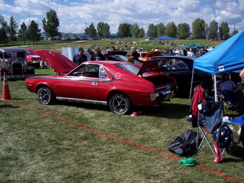 1972 Ford Ranchero - A bright red 1971 AMC AMX is displayed with its hood and trunk open at a car show, with other vehicles and spectators in the background.