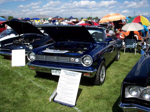 1972 Ford Ranchero - Blue 1965 AMC Rambler American convertible at a car show, with a display sign in front.