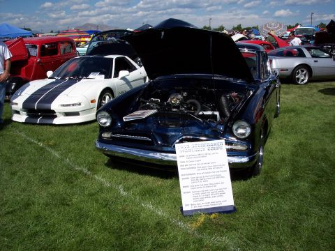 1972 Ford Ranchero - A dark blue 1955 Studebaker President coupe is displayed with its hood open at an outdoor car show.