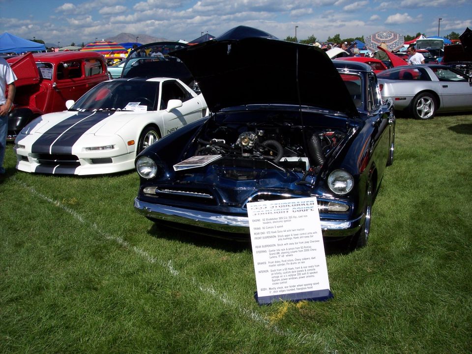 Dark blue 1955 Studebaker President coupe with hood open, showing engine. White sign in front
