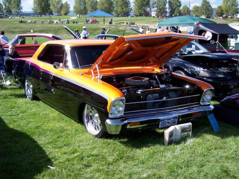 1972 Ford Ranchero - A custom 1967 coupe with a striking orange and black two-tone paint scheme is displayed with its hood open at an outdoor car show.