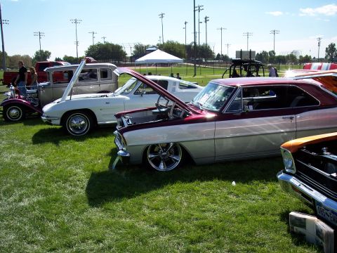 1972 Ford Ranchero - Multiple customized vehicles are displayed on a grassy field under a clear sky, with stadium lights in the background.