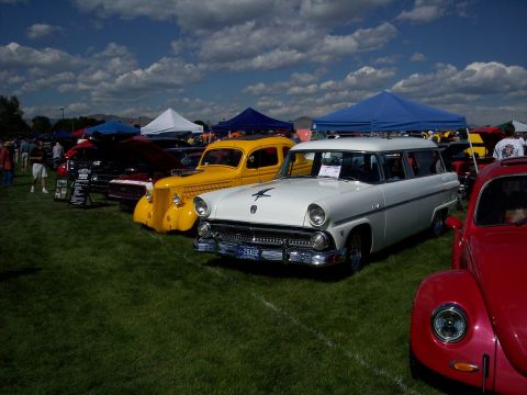 1972 Ford Ranchero - White 1955 Ford station wagon and yellow sedan displayed at an outdoor car show.