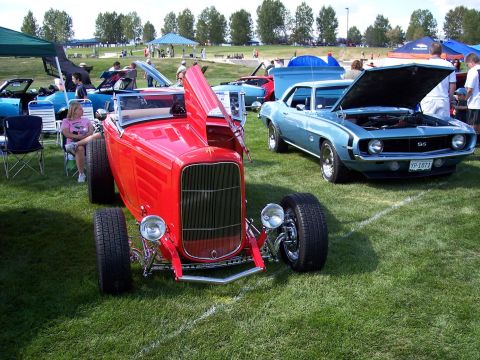 1972 Ford Ranchero - Two classic cars are displayed on a grassy field at an outdoor event, with people and tents in the background.