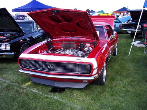 1972 Ford Ranchero - Red 1969 Camaro SS at an outdoor car show, hood and engine exposed.