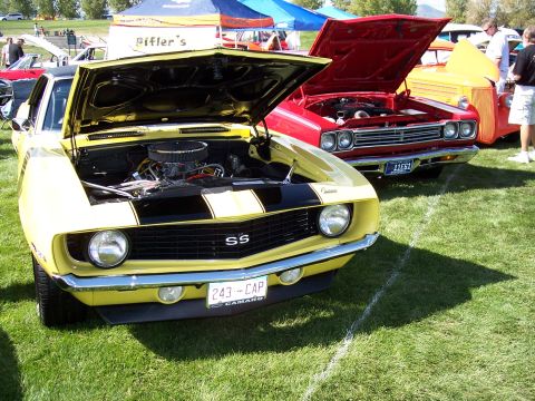1972 Ford Ranchero - A yellow 1969 Chevrolet Camaro SS is parked on a grassy field with its hood open, alongside other vehicles.