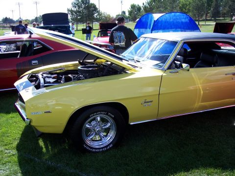 1972 Ford Ranchero - A yellow 1969 Chevrolet Camaro SS is displayed with its hood open at an outdoor car show.