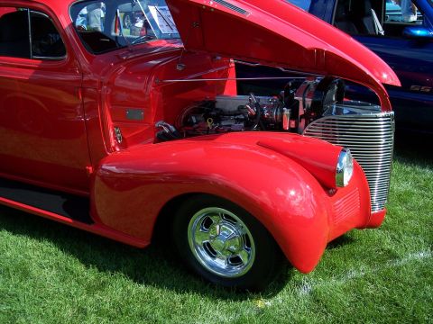 1972 Ford Ranchero - A red classic car is parked on grass with its hood open, revealing the engine and a shiny chrome grille.