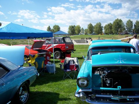 1972 Ford Ranchero - A car show features multiple vintage vehicles displayed on a sunny day with a park setting in the background.