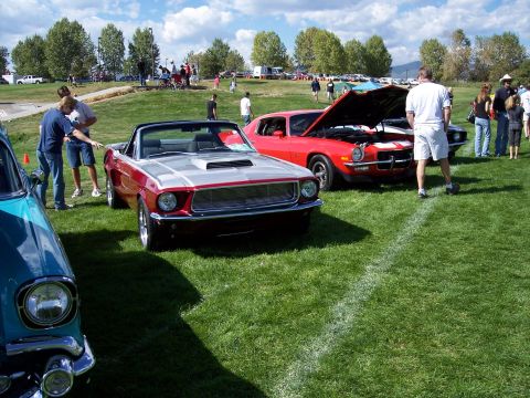 1972 Ford Ranchero - A classic red and silver convertible is displayed at an outdoor car show, with other vehicles and spectators in the background.