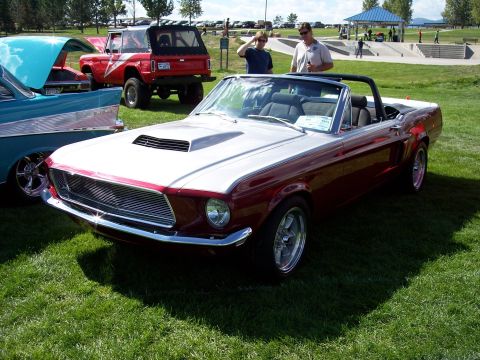 1972 Ford Ranchero - A classic red and silver convertible is displayed at an outdoor event, with other vehicles and people in the background.