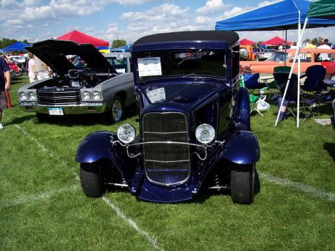 1972 Ford Ranchero - A dark blue hot rod coupe is displayed on a grassy field at an outdoor car show.