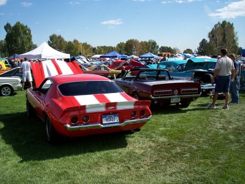 1972 Ford Ranchero - A red 1970 Chevrolet Camaro Z28 is parked on a grassy field at an outdoor car show.
