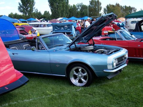 1972 Ford Ranchero - A light blue convertible with its hood open is parked on grass at an outdoor car show, with other vehicles visible in the background.