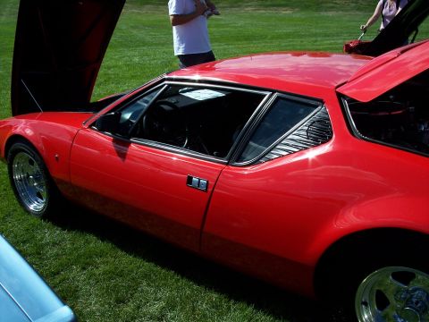 1972 Ford Ranchero - Side view of a red sports car with its hood and trunk open at an outdoor event.