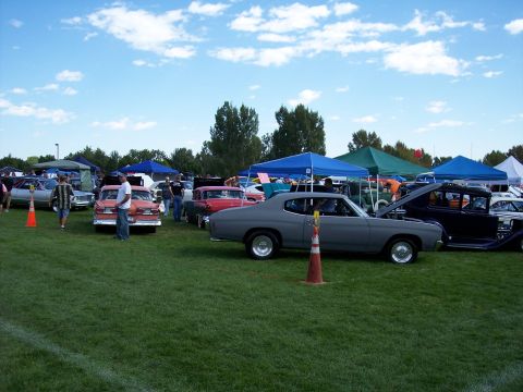 1972 Ford Ranchero - A variety of vintage cars are parked on a grassy field under a partly cloudy sky at an outdoor event.