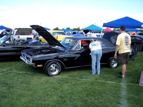 1972 Ford Ranchero - A black muscle car is on display at an outdoor car show with people examining it.