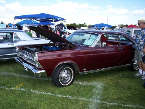 1972 Ford Ranchero - A maroon coupe is displayed at an outdoor event with its hood open, parked on a grassy field.