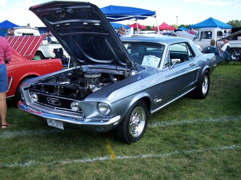 1972 Ford Ranchero - A classic Ford Mustang is displayed with its hood open at an outdoor event, alongside other vehicles and tents.