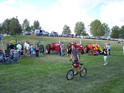1972 Ford Ranchero - An outdoor gathering features several tractors and a line of cars parked on a hill, with people milling about.