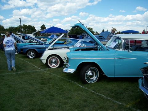 1972 Ford Ranchero - A car show features multiple classic vehicles with their hoods open on a grassy field under a cloudy sky.