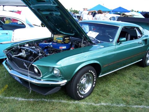 1972 Ford Ranchero - A green 1969 Ford Mustang Mach 1 is displayed with its hood open at an outdoor car show.