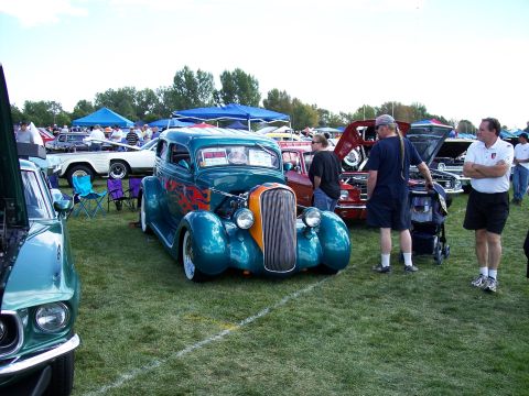 1972 Ford Ranchero - A teal hot rod with custom flame decals is displayed at an outdoor car show.